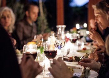 Folk rundt bordet med mat og vin